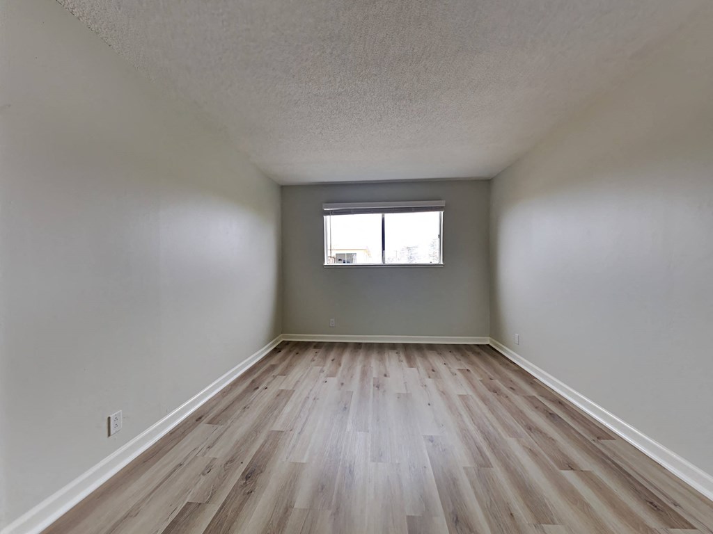 an empty room with wooden floors and a window