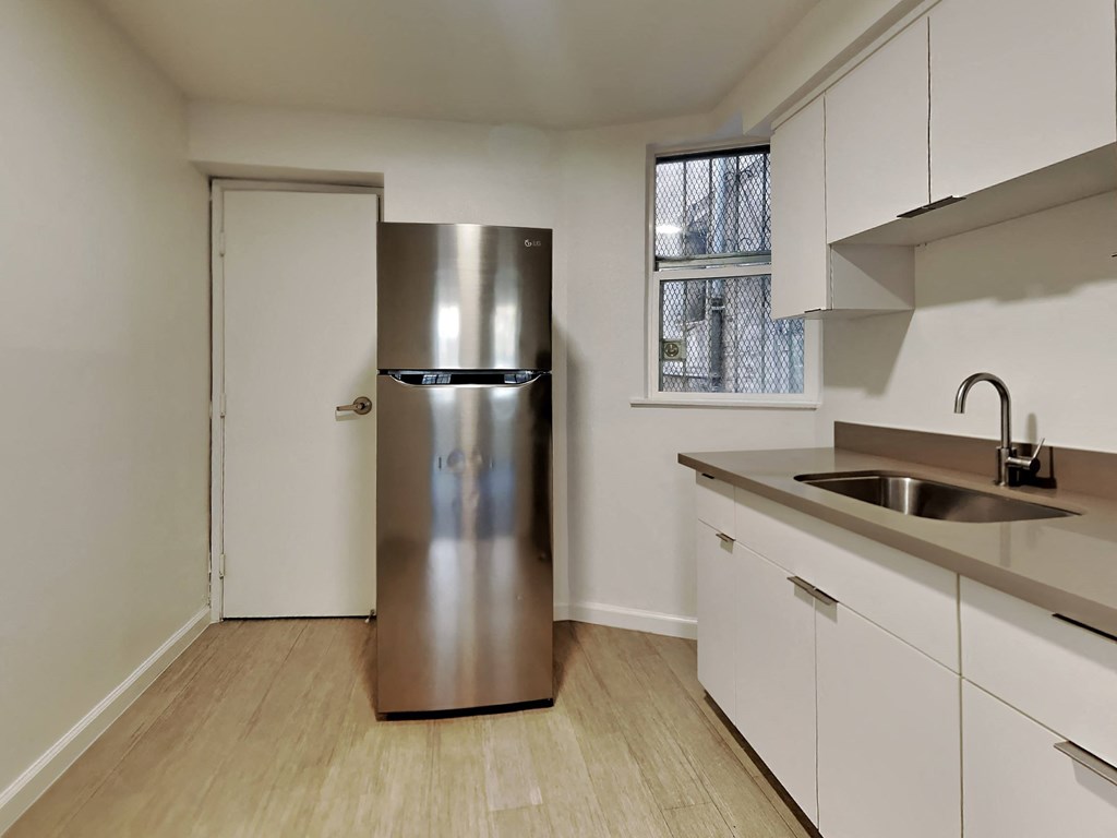 a kitchen with white cabinets and a stainless steel refrigerator
