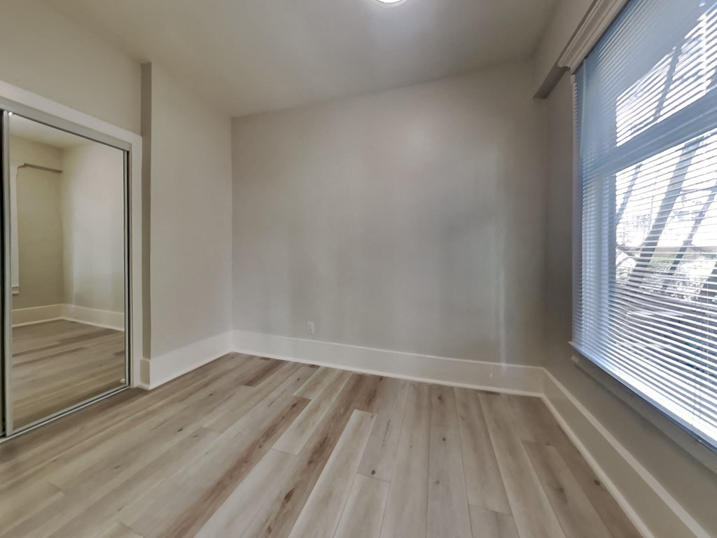 an empty living room with wood flooring and a large window