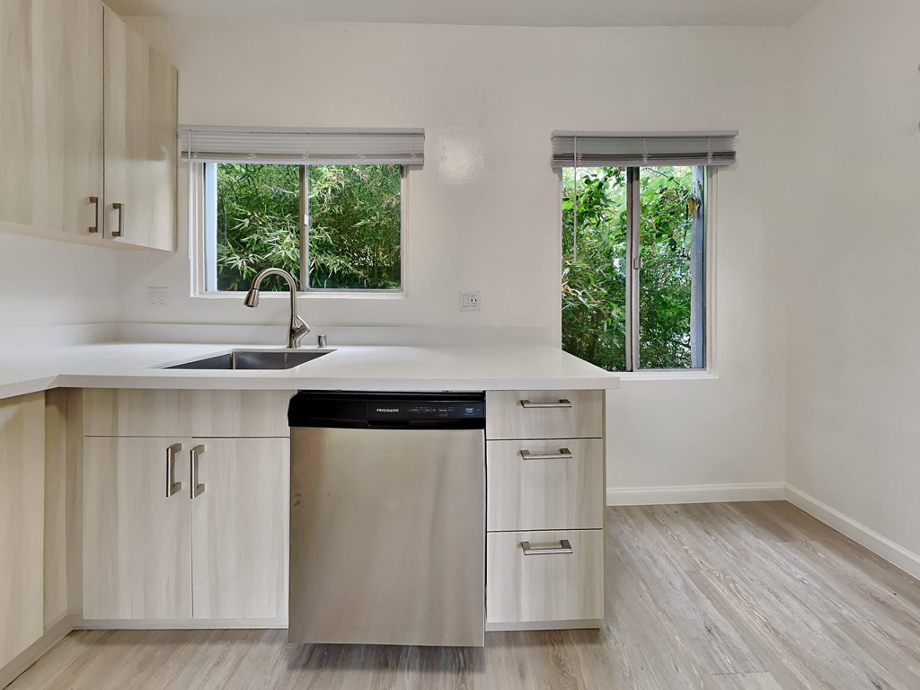 a kitchen with white cabinets and a sink and a window