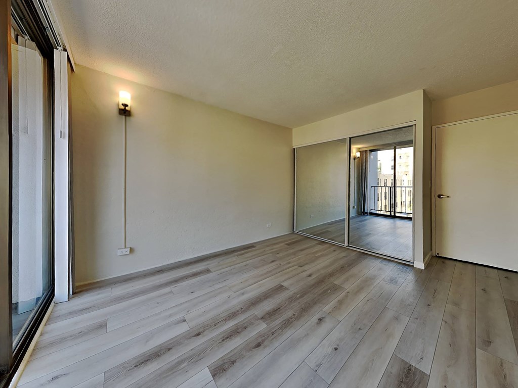 an empty living room with wood floors and a sliding glass door
