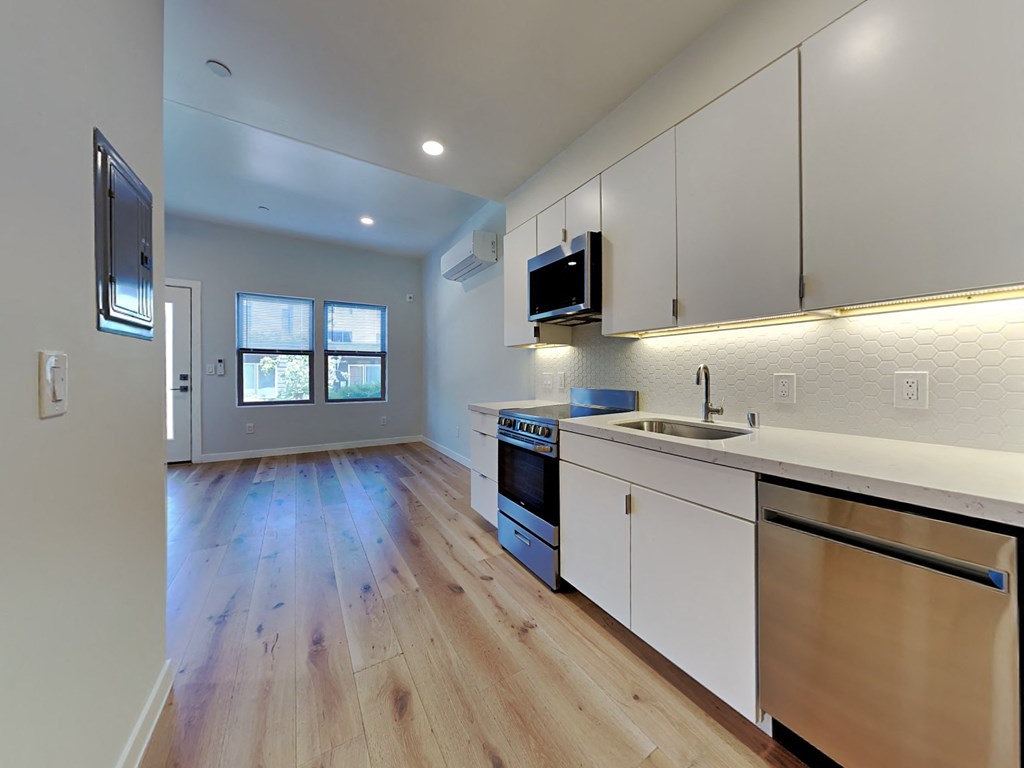 a kitchen with white cabinets and wood floors