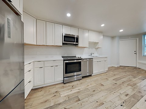 an empty kitchen with white cabinets and stainless steel appliances
