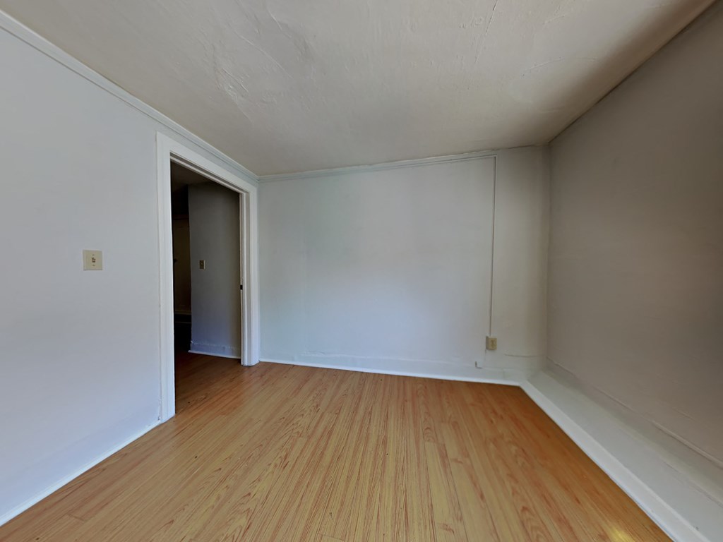 an empty living room with wood floors and white walls