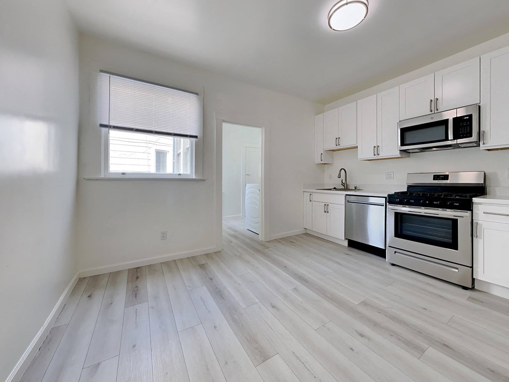 an empty kitchen with white cabinets and stainless steel appliances