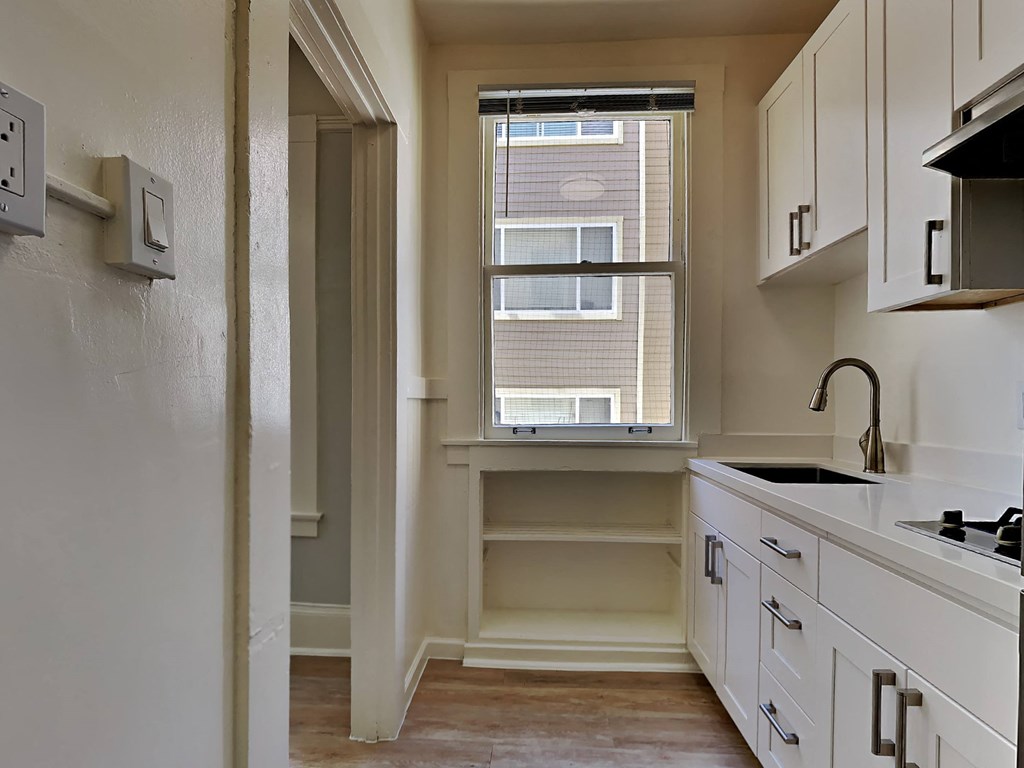 a kitchen with white cabinets and a window