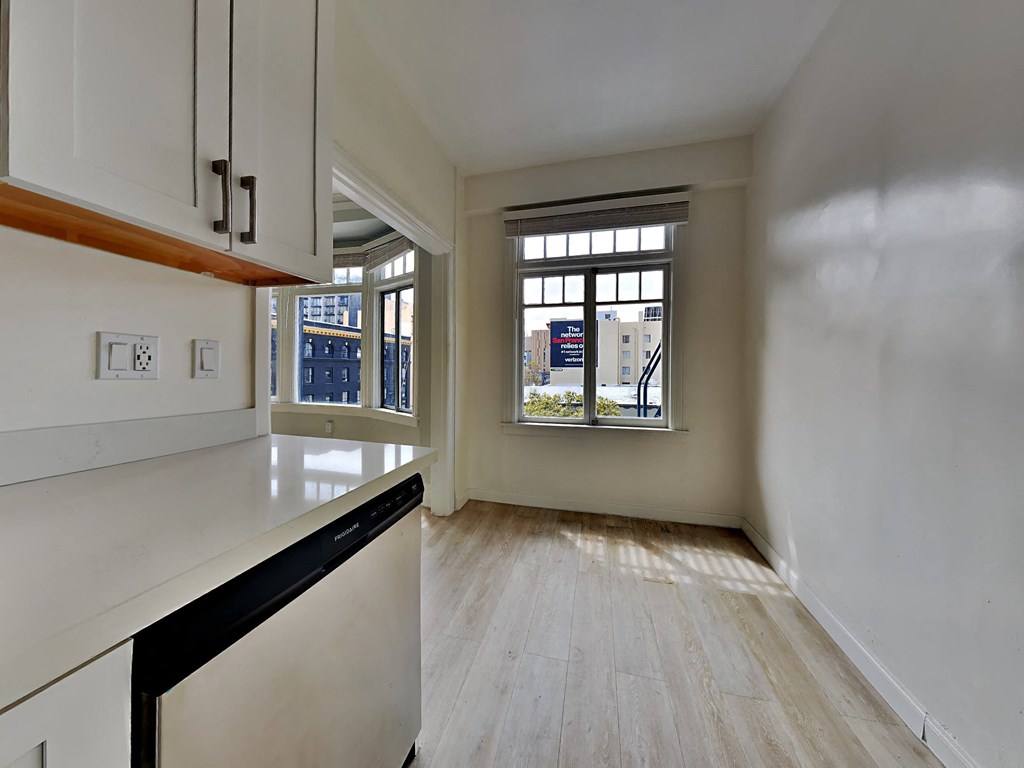 an empty kitchen with white cabinets and a window