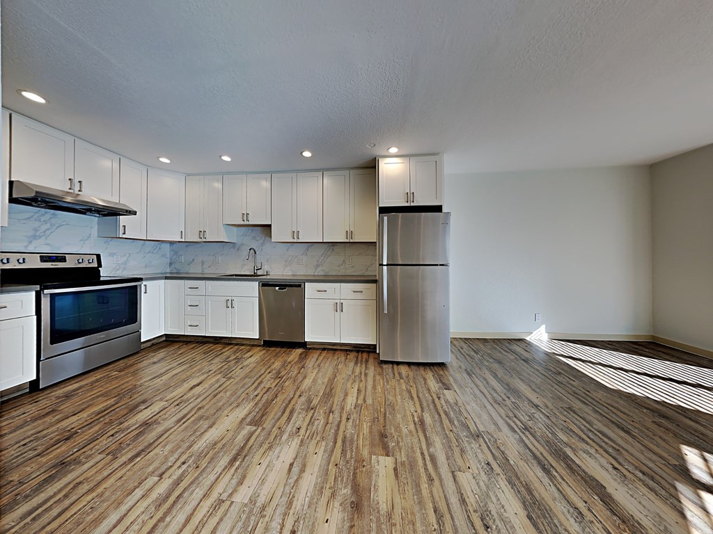 an empty kitchen with white cabinets and stainless steel appliances