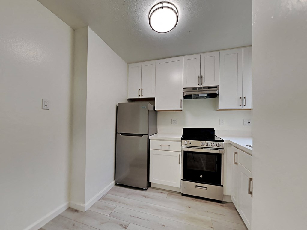 an empty kitchen with white cabinets and stainless steel appliances