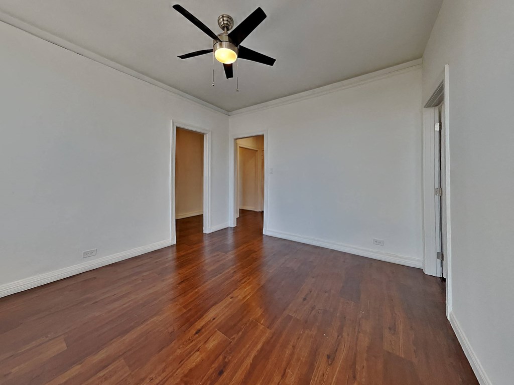 an empty living room with white walls and a ceiling fan