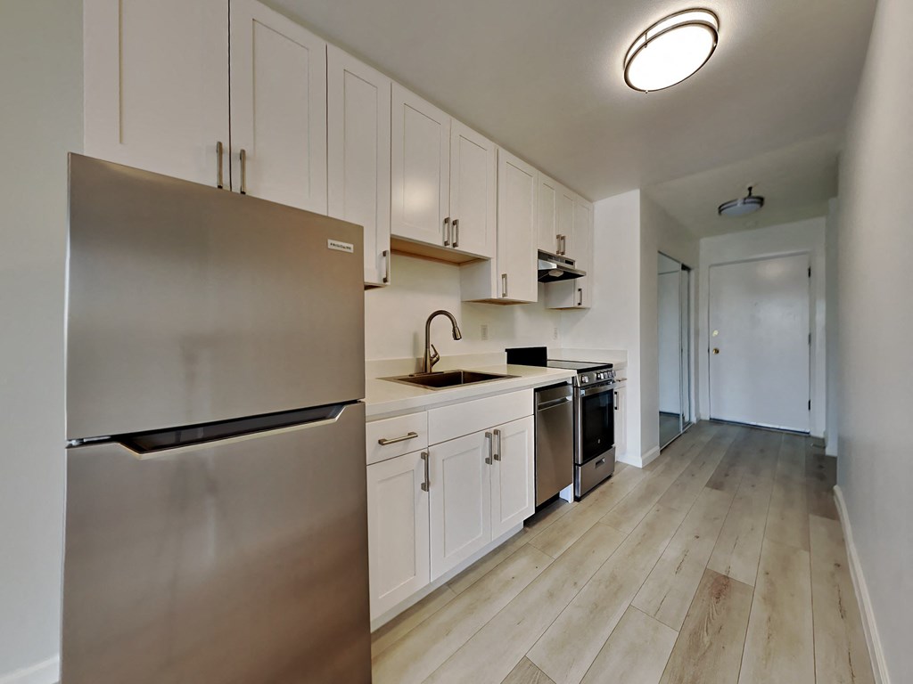 a kitchen with white cabinets and a stainless steel refrigerator