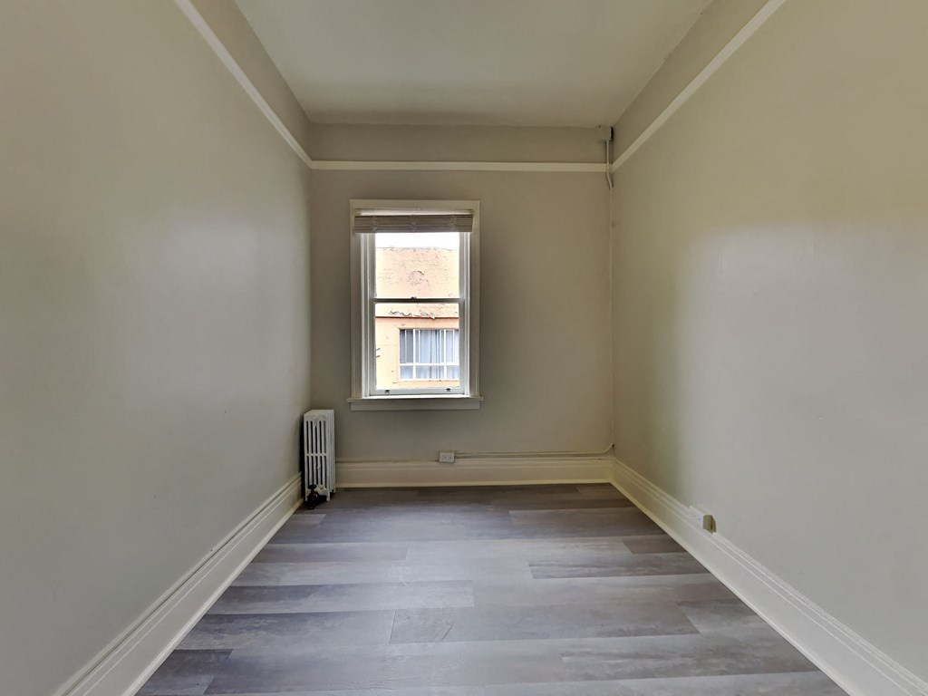 a empty room with a window and wooden floors