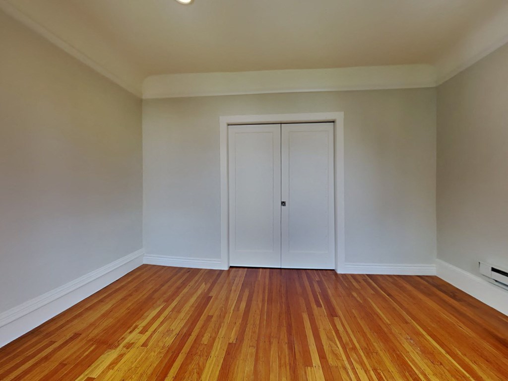 an empty living room with wood floors and white doors