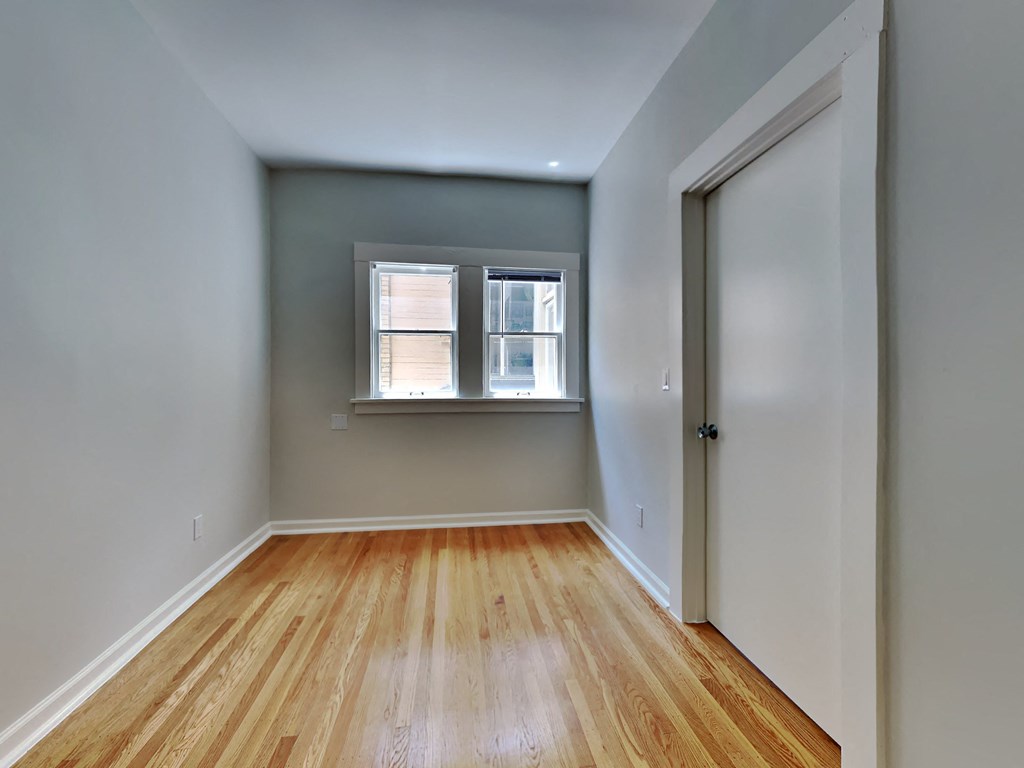 an empty room with wood floors and a window
