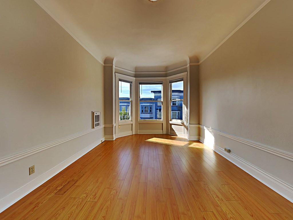 a empty living room with hardwood floors and a window