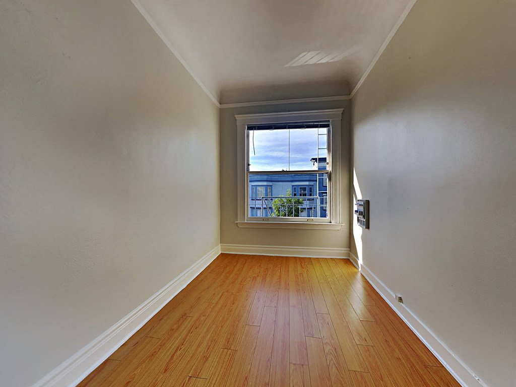 a empty room with a window and wooden floors