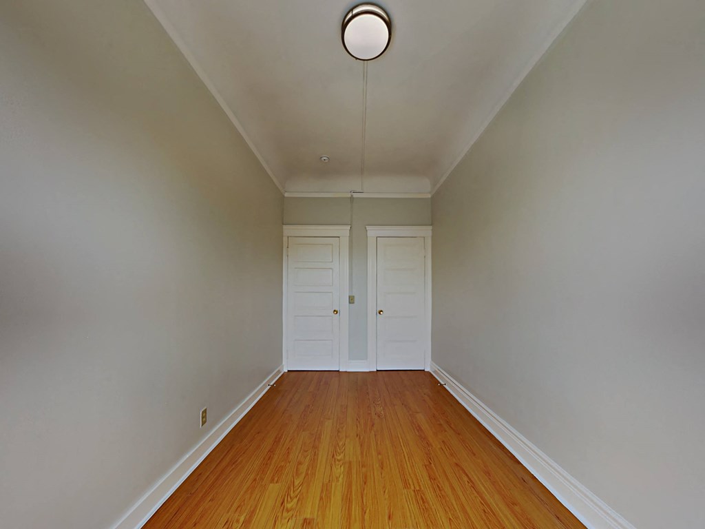 a empty room with wooden floors and white doors