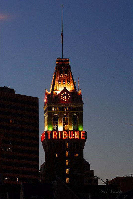 a tall building with a lit up tribune sign at night