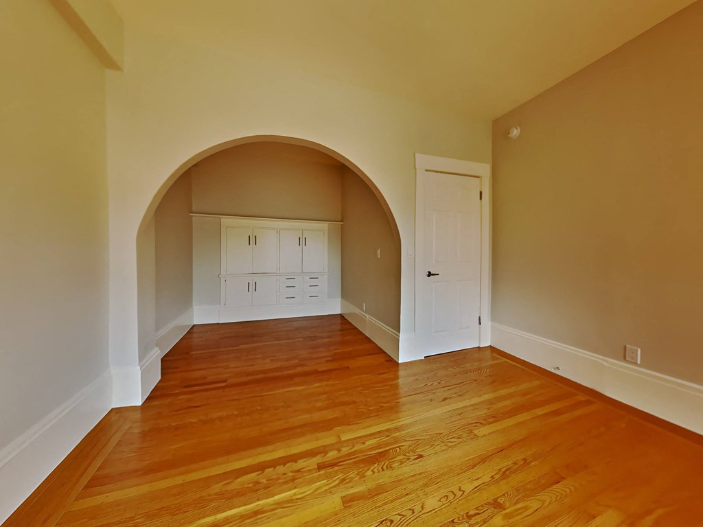 a living room with a wooden floor and an arched doorway