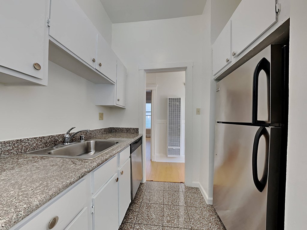 a kitchen with granite counter tops and a stainless steel refrigerator