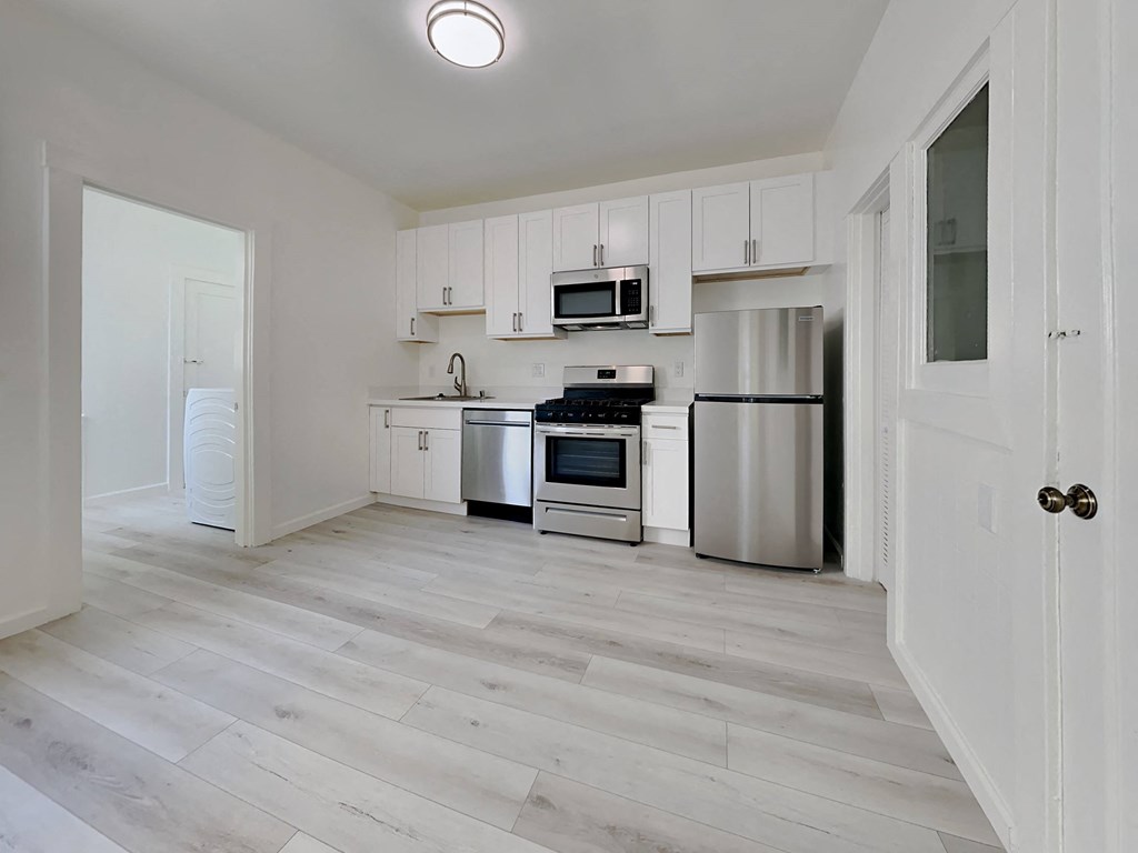 an empty kitchen with white cabinets and stainless steel appliances