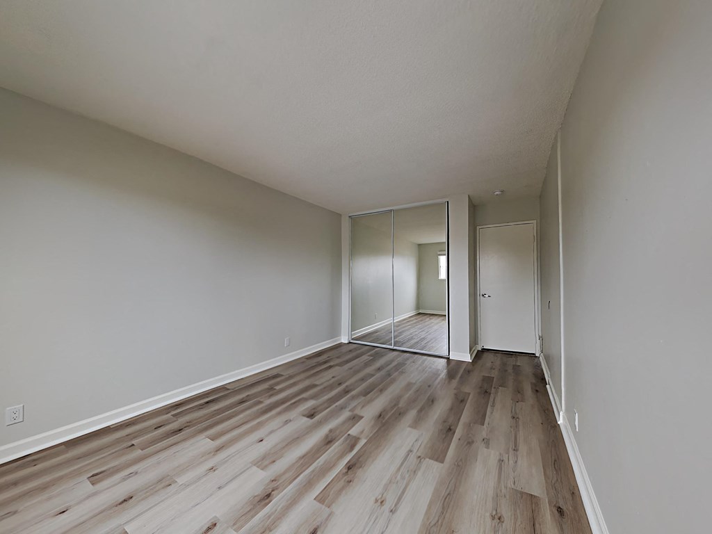 an empty living room with wood flooring and white walls