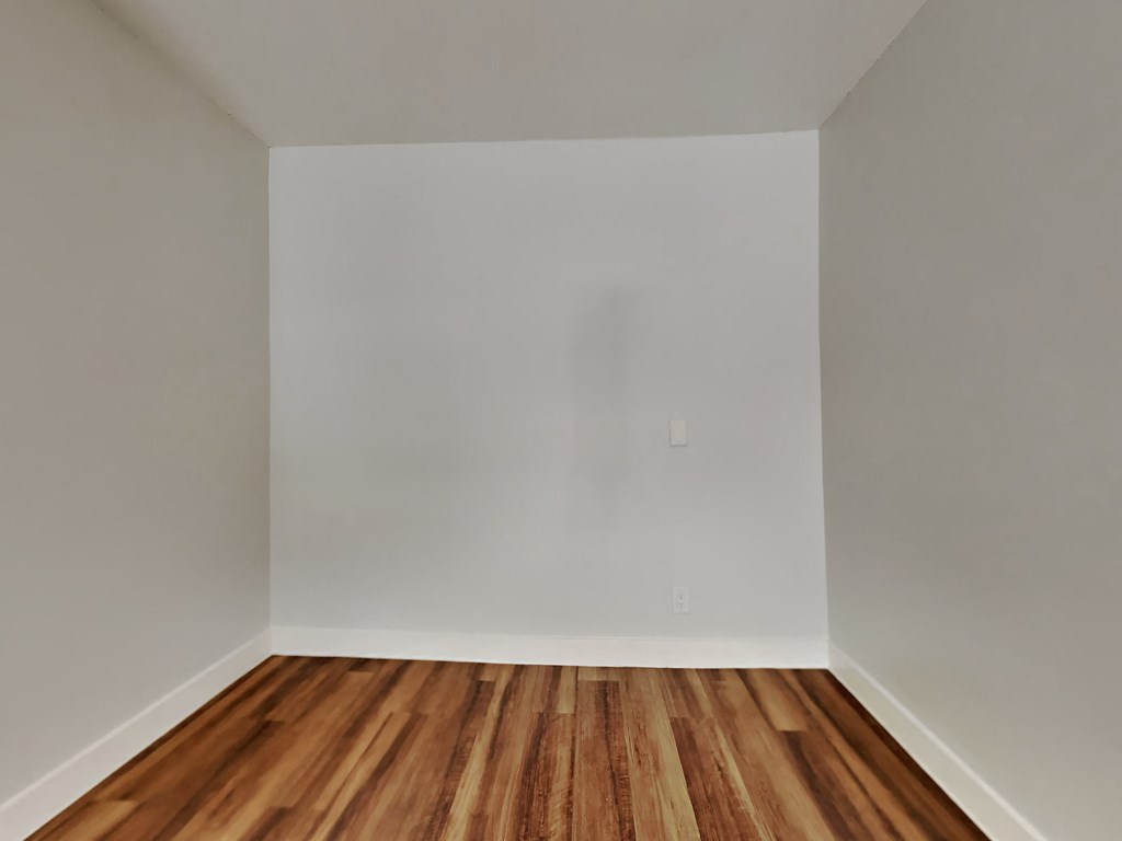 an empty room with white walls and wooden floors