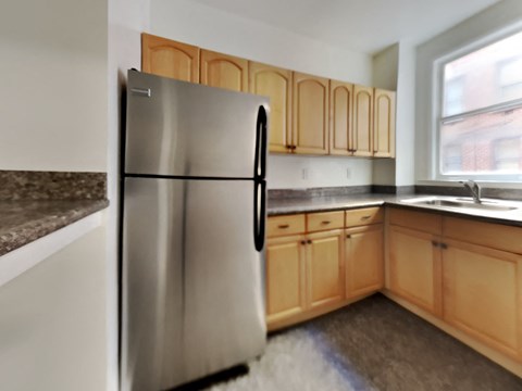 a kitchen with a stainless steel refrigerator and wooden cabinets