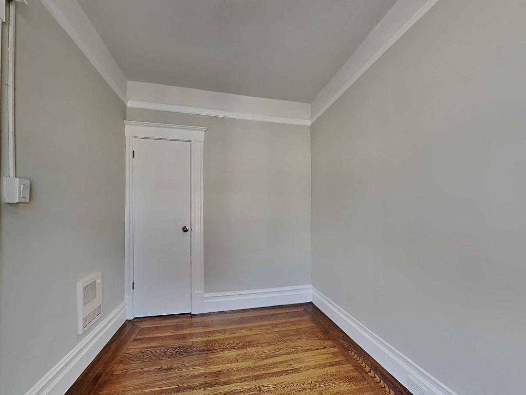 a bedroom with wood flooring and a white door
