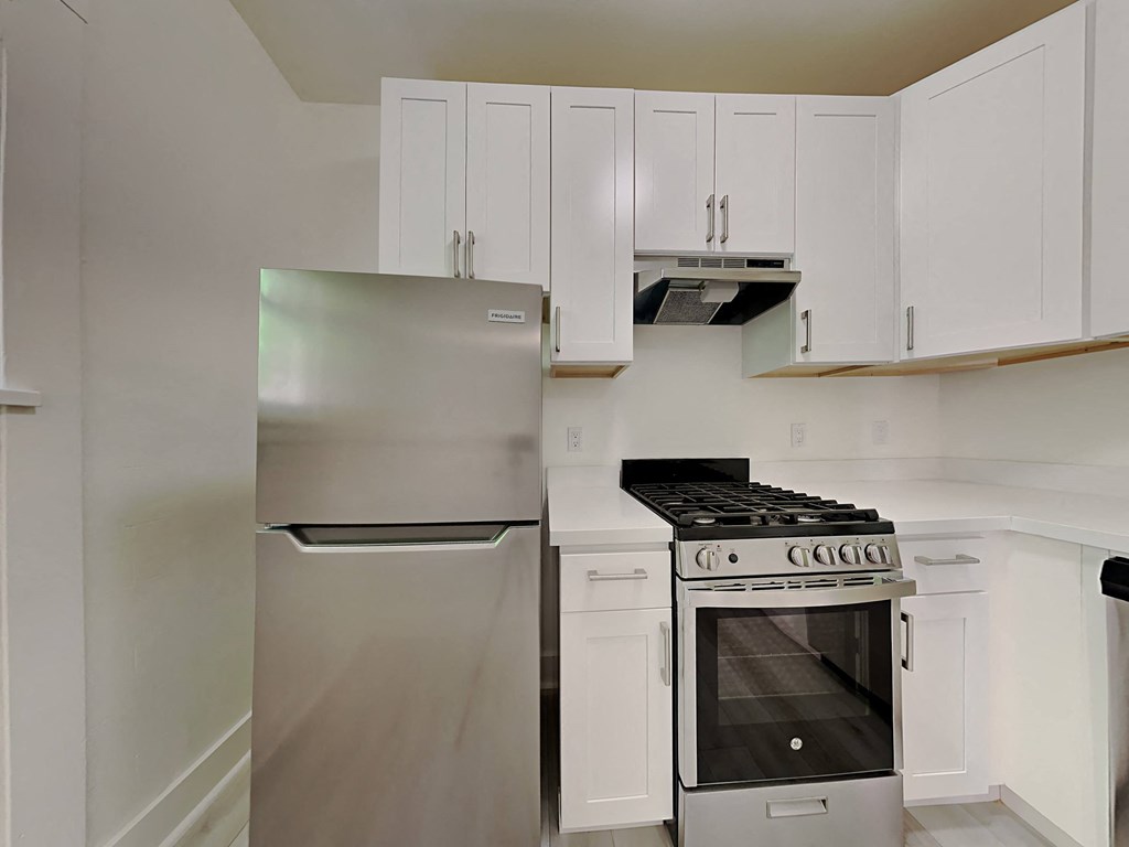 a white kitchen with stainless steel appliances and white cabinets