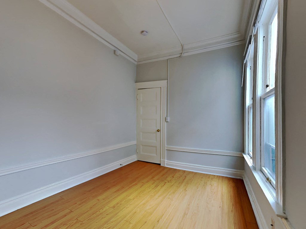 a living room with white walls and a wooden floor and a door
