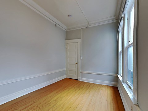 a living room with white walls and a wooden floor and a door