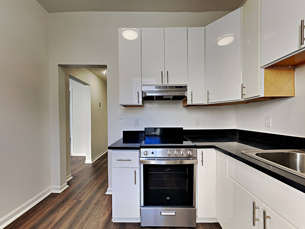 a kitchen with white cabinets and black counter tops and a stove