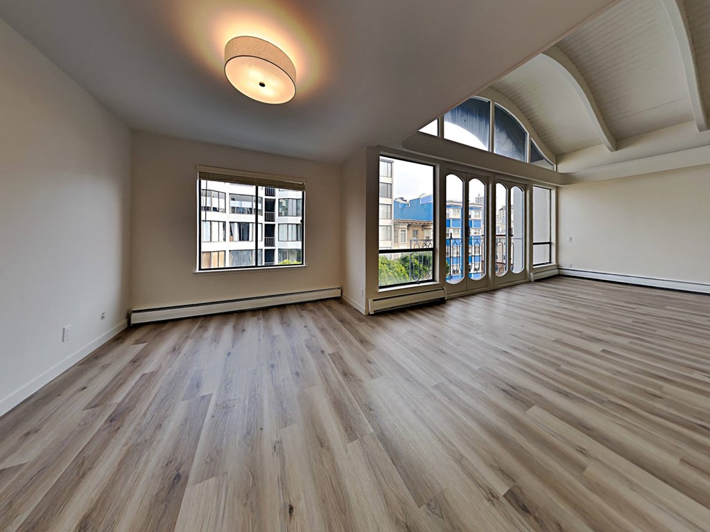 an empty living room with wood flooring and large windows
