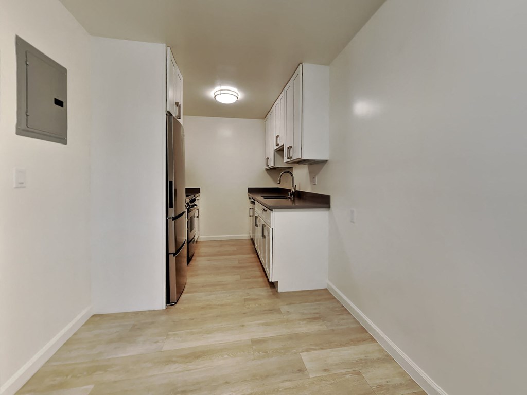 an empty kitchen with white walls and wood floors