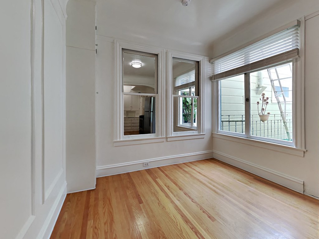a living room with three windows and wood floors