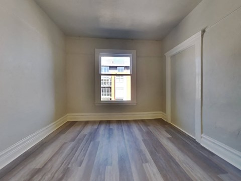 an empty room with a window and wooden floors