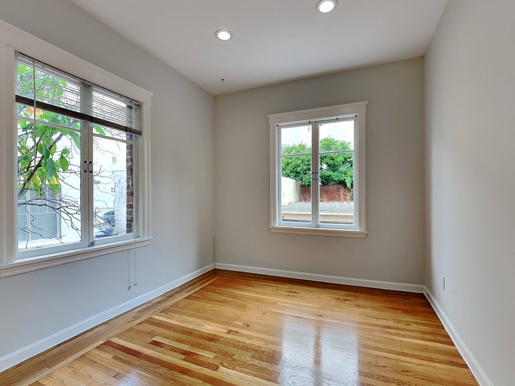 a living room with a hardwood floor and two windows