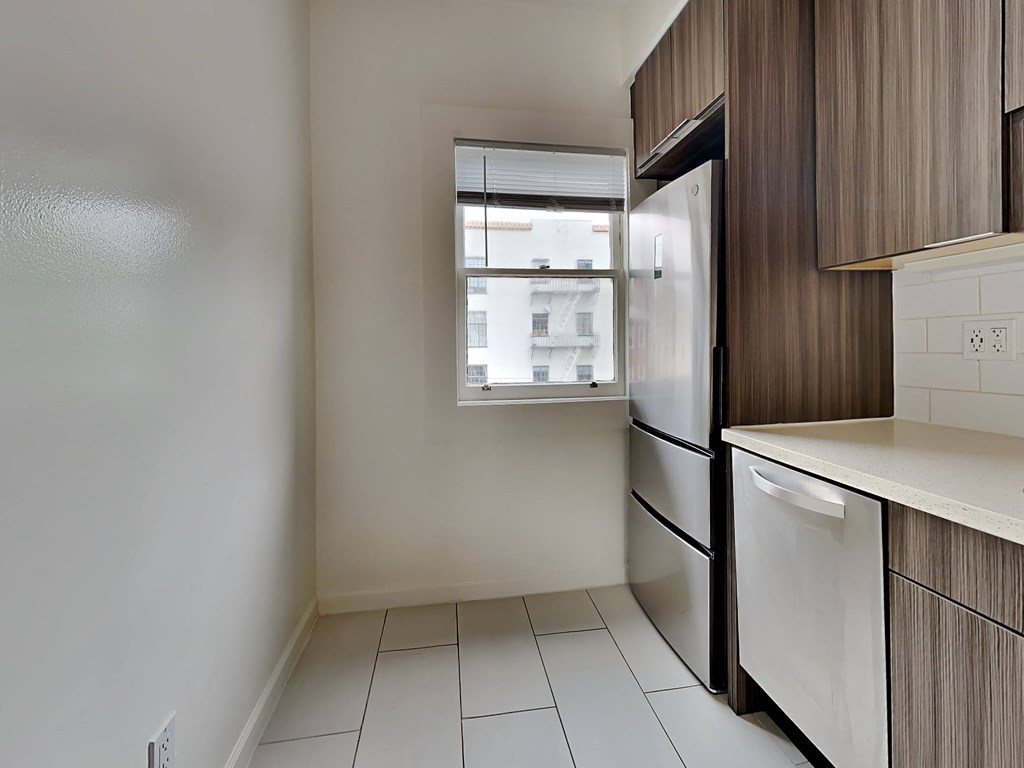 an empty kitchen with a refrigerator and a window