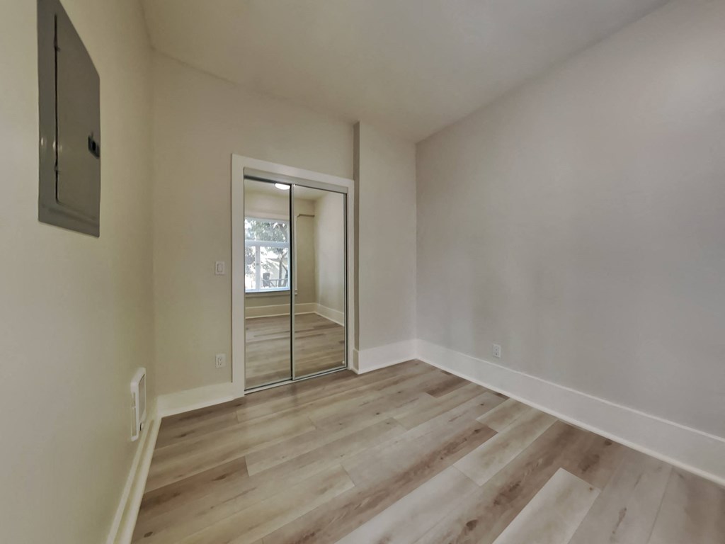 an empty living room with a sliding glass door to a hallway