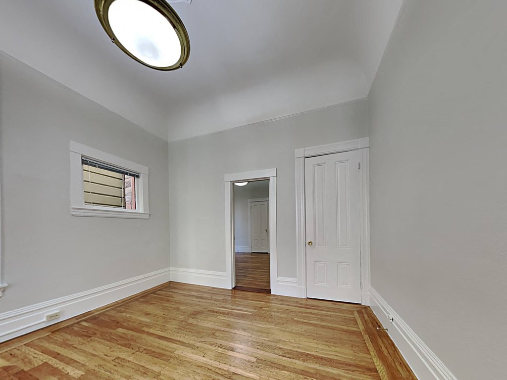 an empty living room with a door to a hallway and a window