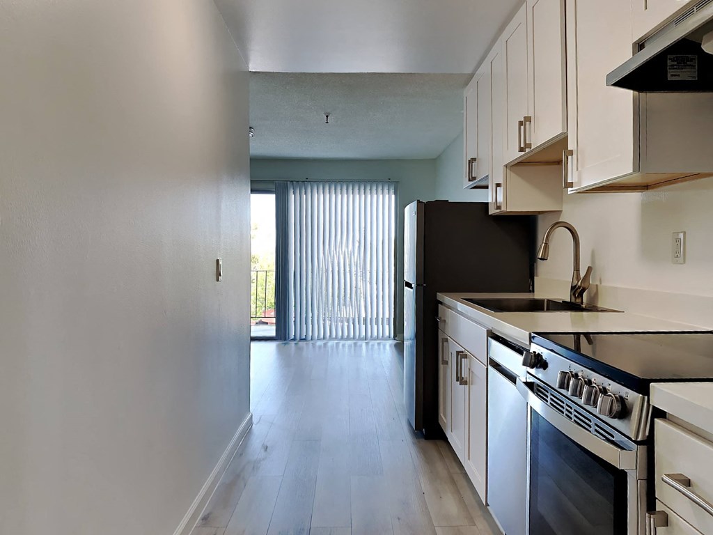an empty kitchen with white cabinets and a black refrigerator and stove