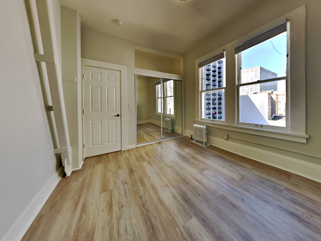 an empty living room with a large window and wooden floors