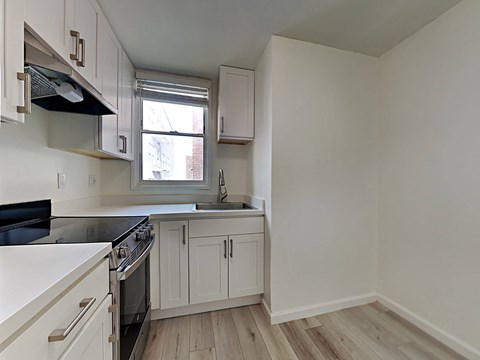 an empty kitchen with white cabinets and a window