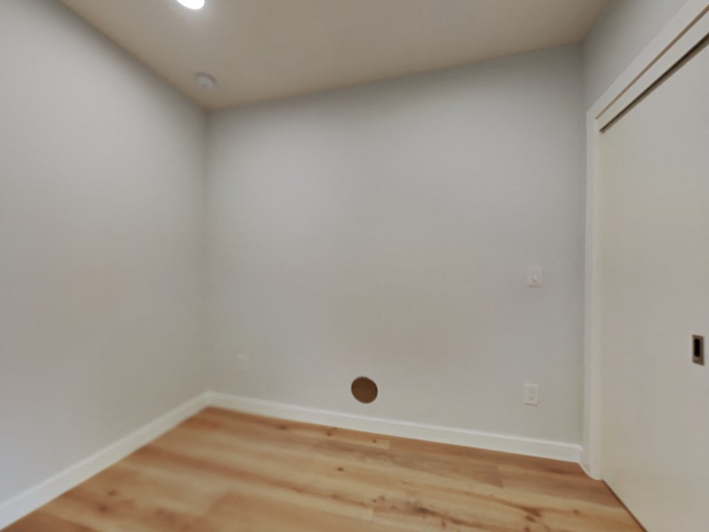 an empty room with a wooden floor and a white wall