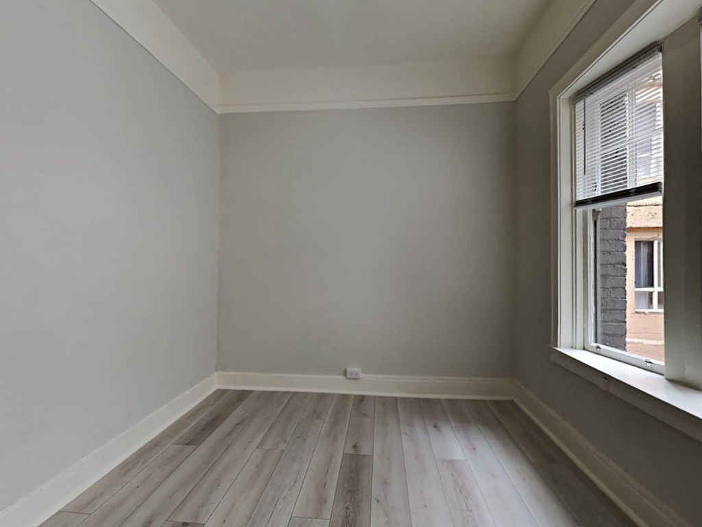 an empty room with a window and wooden floors