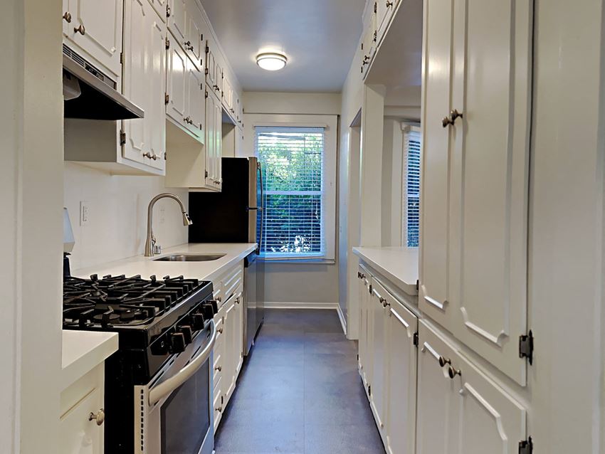 a kitchen with white cabinets and a stove and a window