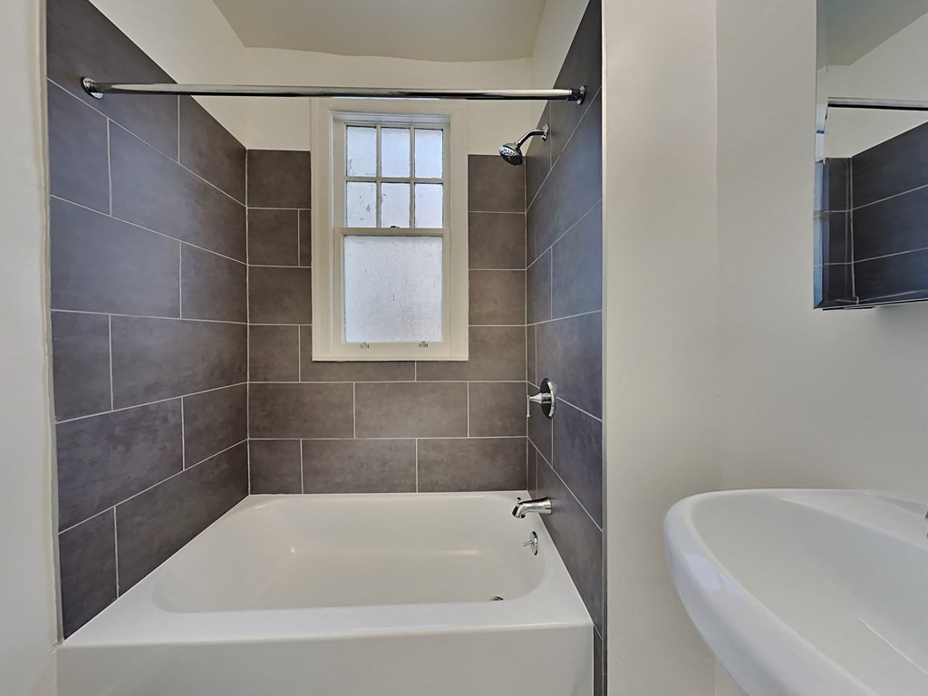 a bathroom with a tub and a sink and a window