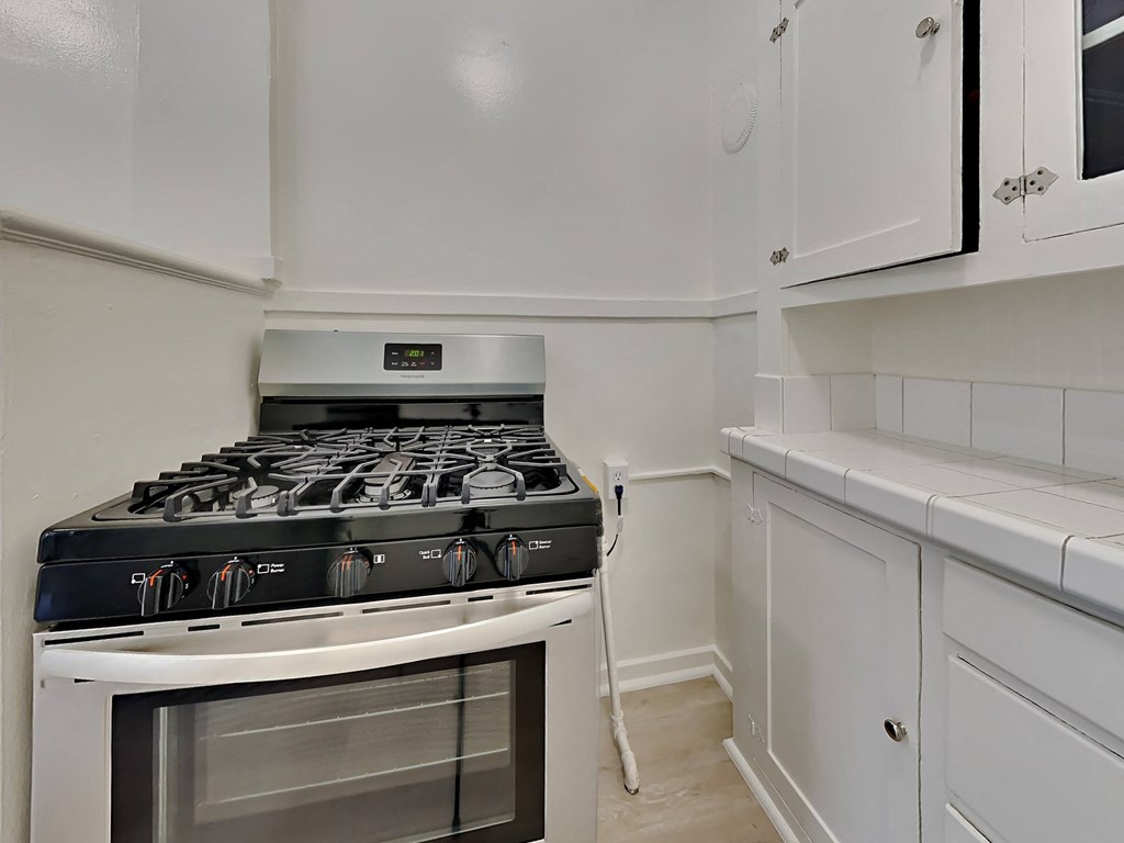 the kitchen of a home with a stove and white cabinets