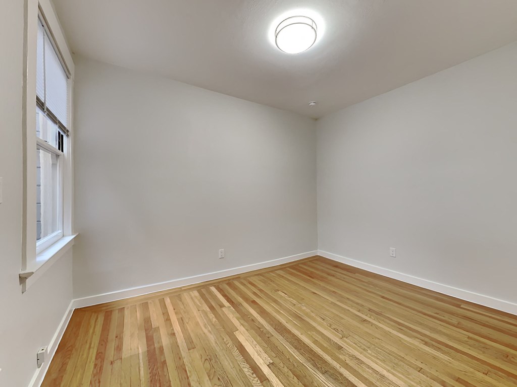 an empty room with wood flooring and a window